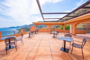 a patio with tables and chairs and a view of the ocean at Baia Taormina - CDSHotels in Forza dʼAgro