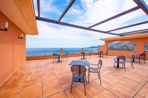 a patio with tables and chairs and a view of the ocean at Baia Taormina - CDSHotels in Forza dʼAgro