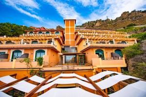 a house in the mountains with a group of white chairs at Baia Taormina - CDSHotels in Forza dʼAgro