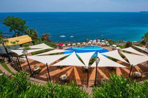 a view of a pool with umbrellas and the ocean at Baia Taormina - CDSHotels in Forza dʼAgro
