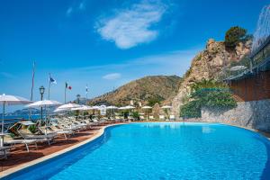 a swimming pool with chairs and umbrellas at a resort at Baia Taormina - CDSHotels in Forza dʼAgro