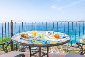 a table with food and drinks on a balcony overlooking the ocean at Baia Taormina - CDSHotels in Forza dʼAgro