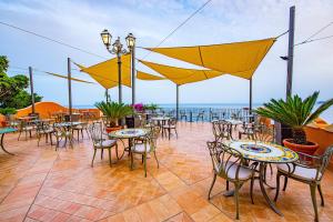 a patio with tables and chairs with the ocean in the background at Baia Taormina - CDSHotels in Forza dʼAgro