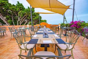 a long table with chairs and an umbrella on a patio at Baia Taormina - CDSHotels in Forza dʼAgro
