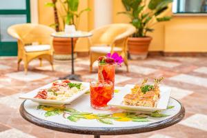 a table with two plates of food and drinks at Baia Taormina - CDSHotels in Forza dʼAgro