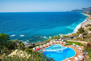 a view of the ocean from a resort with a swimming pool at Baia Taormina - CDSHotels in Forza dʼAgro