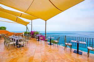 a patio with tables and chairs and the ocean at Baia Taormina - CDSHotels in Forza dʼAgro