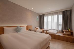 Una habitación de hotel con dos camas y una ventana. en In Joy Hotel, en Taichung 37 fotos más