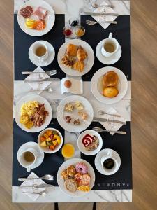 a table with plates of food and cups of coffee at HÔTEL & SPA Panorama 360 in Mâcon