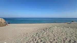 a sandy beach with people on the water at Baia Taormina - CDSHotels in Forza dʼAgro
