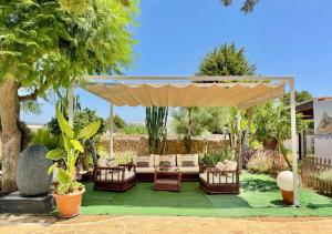 une pergola avec des chaises et un canapé sous celle-ci dans l'établissement Villa Walk To O Beach Large Pool Bbq, à Sant Antoni de Portmany