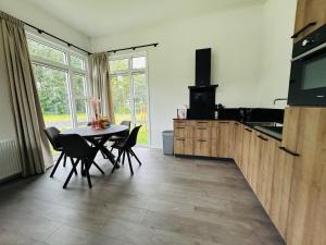 a kitchen with a table and chairs and a television at Bungalowpark de Horn - Floresta 214 in Dirkshorn