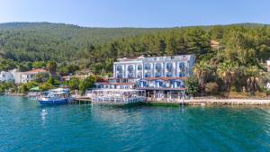 a hotel on the water with two boats in the water at Akyalı Boutique Hotel in Guvercinlik
