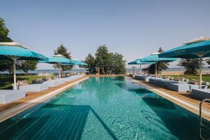 a swimming pool with blue umbrellas and chairs at Nayu Igneada in Demirköy