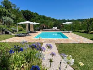 a swimming pool in a yard with purple flowers at Agriturismo Colpo di Fortuna in Gualdo di Macerata