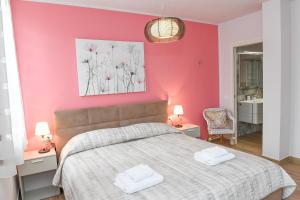 a bedroom with a large bed with a pink wall at Favolabella Collection in Bardolino