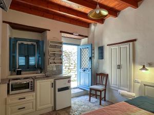 a kitchen with white cabinets and a table and a chair at Symi Uptown Carmine in Symi