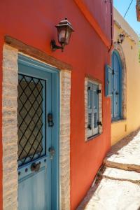 an orange building with a blue door and a lamp at Symi Uptown Carmine in Symi