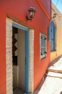an orange building with a blue door and a lamp at Symi Uptown Carmine in Symi