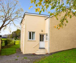 a small yellow building with a white door at Soar Cottage Aberystwyth in Aberystwyth