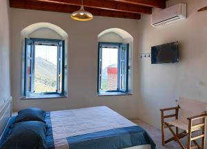a bedroom with two windows and a bed and a chair at Symi Uptown Carmine in Symi