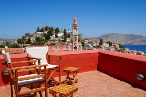 a balcony with chairs and a table and a view at Symi Uptown Carmine in Symi