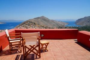 two chairs and a table on a balcony overlooking the ocean at Symi Uptown Carmine in Symi