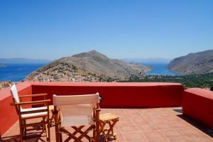 a balcony with chairs and a view of the ocean at Symi Uptown Carmine in Symi