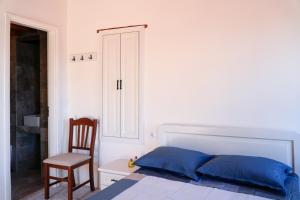 a white bedroom with a bed and a chair at Symi Uptown Carmine in Symi