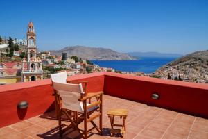 two chairs on a balcony with a view of the city at Symi Uptown Carmine in Symi