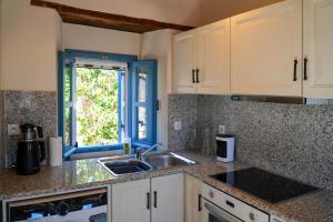 a kitchen with white cabinets and a sink and a window at Symi Uptown Carmine in Symi