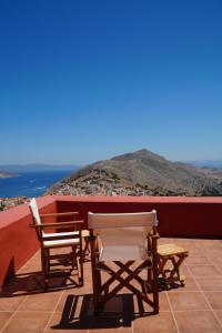 two chairs and a table on a balcony with the ocean at Symi Uptown Carmine in Symi