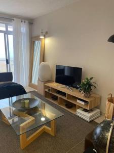 a living room with a television and a table at A zen and chic beachfront apartment in Swakopmund