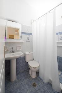 een badkamer met een wit toilet en een wastafel bij Villa Porto Rondo in Agios Prokopios