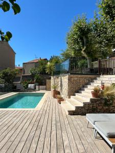 a swimming pool with a wooden deck and stairs at Maï Homes - La Villa Bompard in Marseille