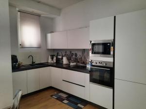 Una cocina con gabinetes blancos y un microondas. en Il filo di Arianna, en Putignano