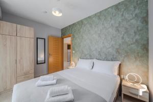 une chambre avec un lit blanc et un mur vert dans l'établissement P Deluxe Suites A4, à Néa Michanióna