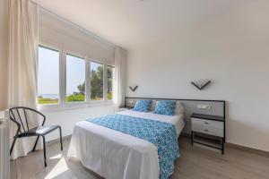 ein Schlafzimmer mit einem Bett und einem Stuhl und einem Fenster in der Unterkunft Bravissimo Vil·les Brusi C S'Agaró in S'Agaró