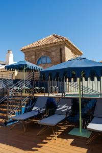 a group of chairs and umbrellas next to a pool at Palacio Solecio, a Small Luxury Hotel of the World in M&aacute;laga