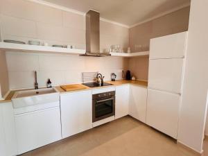a white kitchen with a sink and a stove at Beachfront Nudist Apartment in Vera Playa in Playas de Vera +6 photos