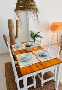 a dining room table with white chairs and a wooden table with plates at Beachfront Nudist Apartment in Vera Playa in Playas de Vera