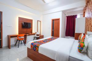 a bedroom with a bed and a desk with a computer at FabHotel Royal Platinum Suites in Bengaluru