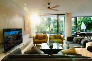 un salon avec des canapés et une télévision à écran plat dans l'établissement Villa Luxury 5 Phòng ngủ Hồ bơi riêng - Resort Sanctuary Hồ Tràm, à Xuyên Mộc