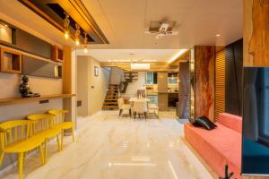 ロナバラにあるAlaya Stays - Imperial Mystara 5BHK near Khandala Hillsの黄色とオレンジ色の椅子が置かれたリビングルームとダイニングルーム