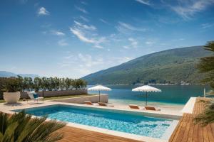 a swimming pool with two umbrellas and the water at One&Only Portonovi in Herceg-Novi