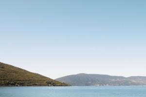 a large body of water with mountains in the background at One&Only Portonovi in Herceg-Novi