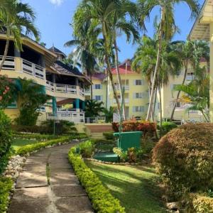 a walkway in front of a building with palm trees at Comfort Zone at The Ridge E17 in Ocho Rios