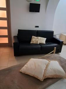 eine schwarze Couch in einem Wohnzimmer mit einem Kissen in der Unterkunft Casa Angolo dei Sogni in Martina Franca
