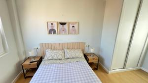 a bedroom with a bed with two nightstands and two pictures at Acogedor apartamento en Ronda Outeiro 210 in A Coruña