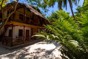 a house with a palm tree in front of it at Eden Paradise in Michamvi